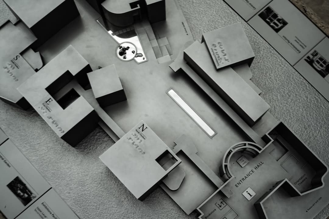 A brightly lit, modern desk with architectural blueprints, a laptop, and drafting tools, symbolizing a strategic plan for real estate data governance.