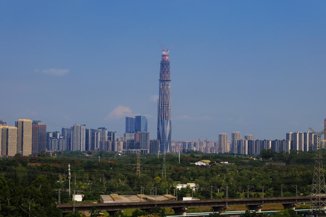 A striking shot looking up at a single, modern glass skyscraper that towers above all surrounding buildings against a clear blue sky, symbolizing market dominance and visibility.