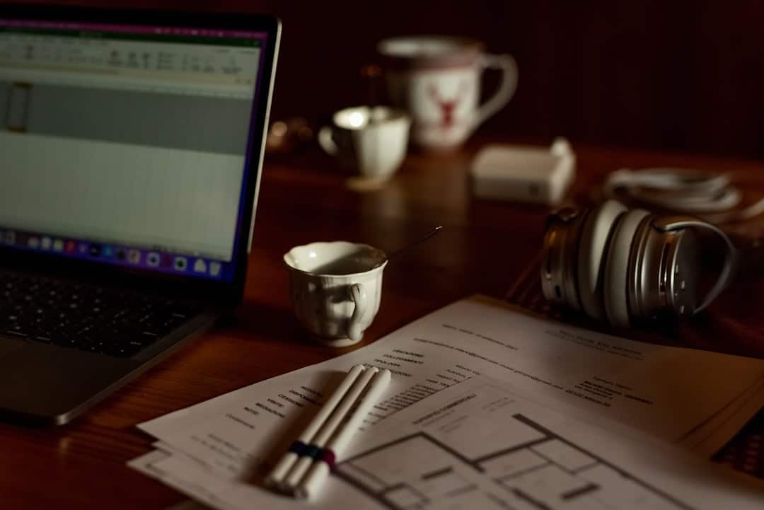 Close-up of an architectural blueprint spread across a modern wooden desk, symbolizing strategic planning and system desig...