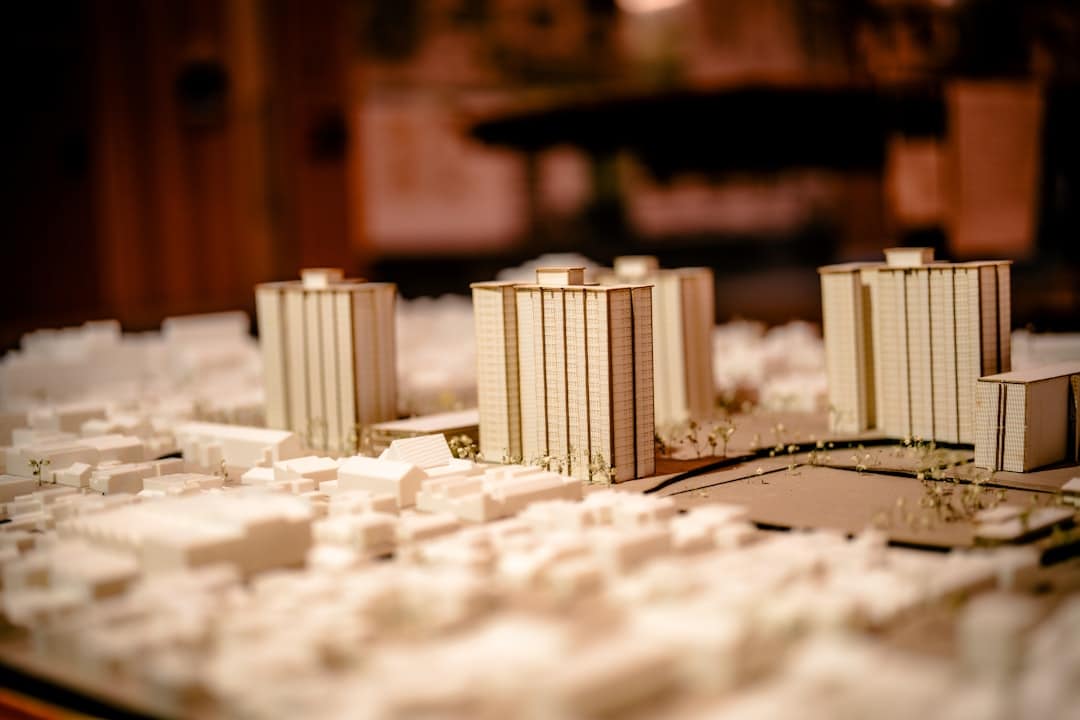 Close-up of several pairs of hands carefully assembling a detailed architectural model, symbolizing collaboration and buil...