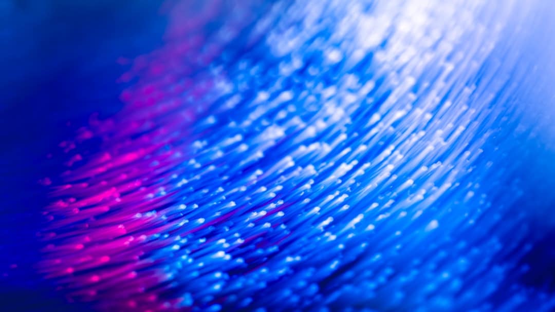 Close-up of a chaotic tangle of glowing fiber optic cables on a dark background, symbolizing complex and fragmented data s...