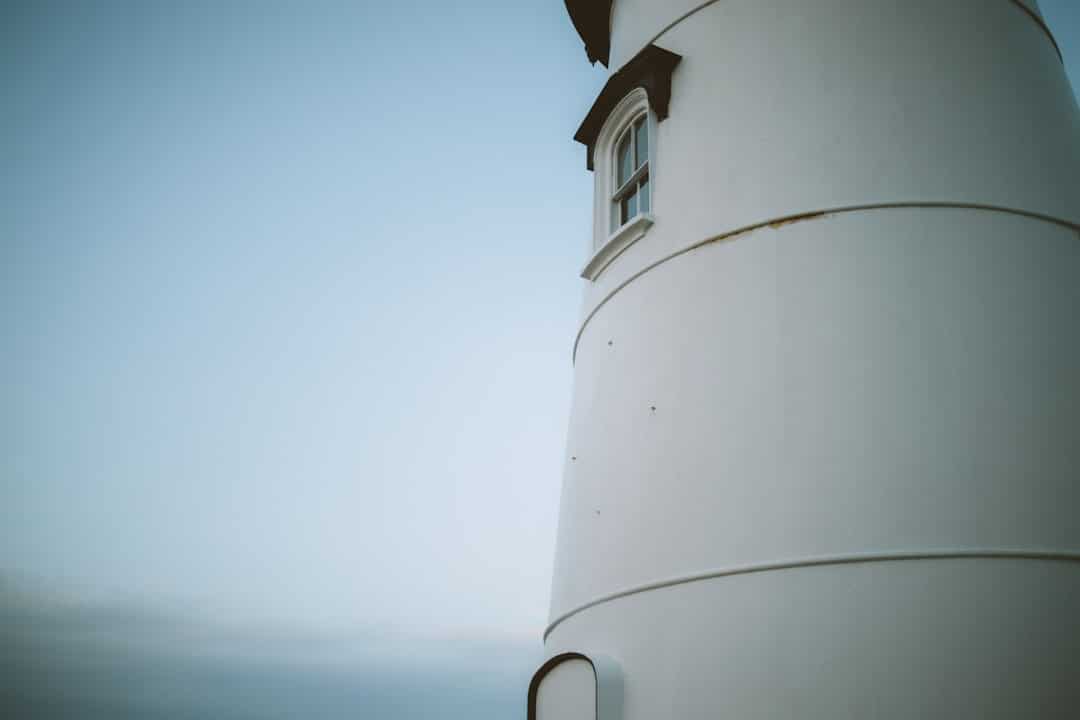 A modern, minimalist lighthouse standing as a clear beacon against a bright sky, symbolizing a definitive and authoritative source of information.