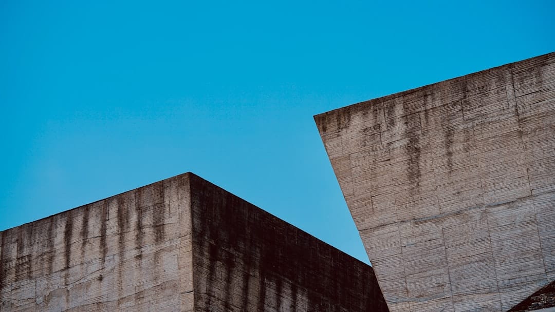Close-up architectural detail shot of a concrete building wall with visible cracks and decay, symbolizing the concept of k...