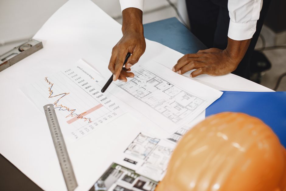 Expert in a bright, modern office meticulously reviewing a complex set of blueprints, representing clarity in a detailed S...