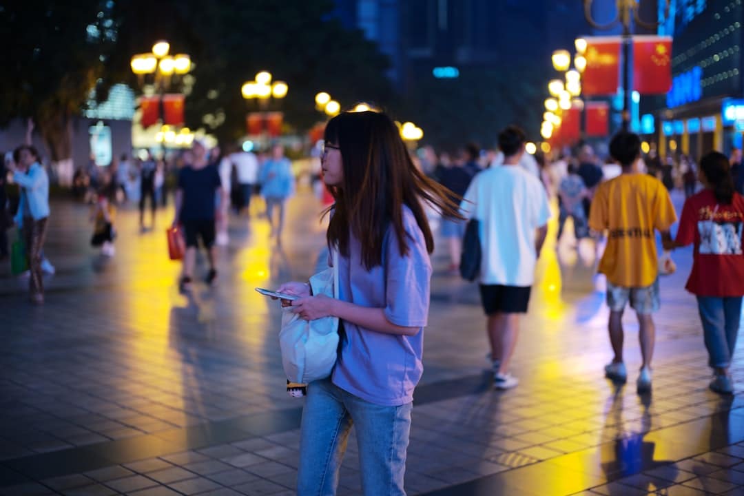 A woman stands on a clean city street looking down at her smartphone which displays a map, representing a successful local search for a business or directions.