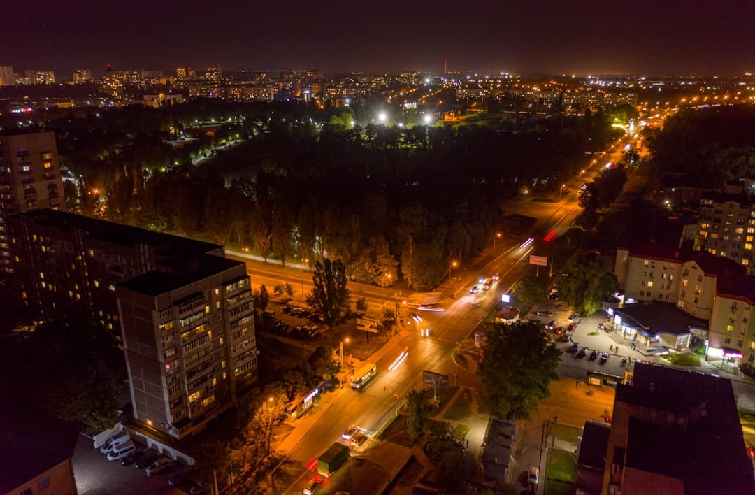 An aerial photograph of a bustling city at night, with long exposure light trails from traffic creating a sense of dynamic energy and connection throughout the urban market.