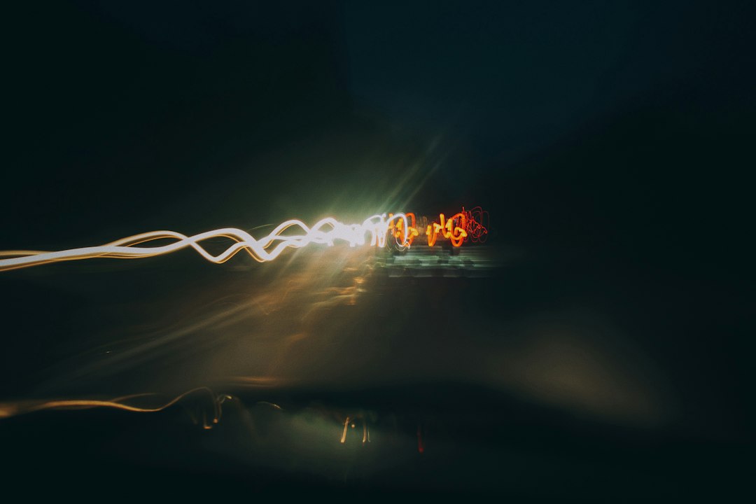 An abstract photo of two distinct streams of light converging into one against a dark background, representing the merging of digital ecosystems.