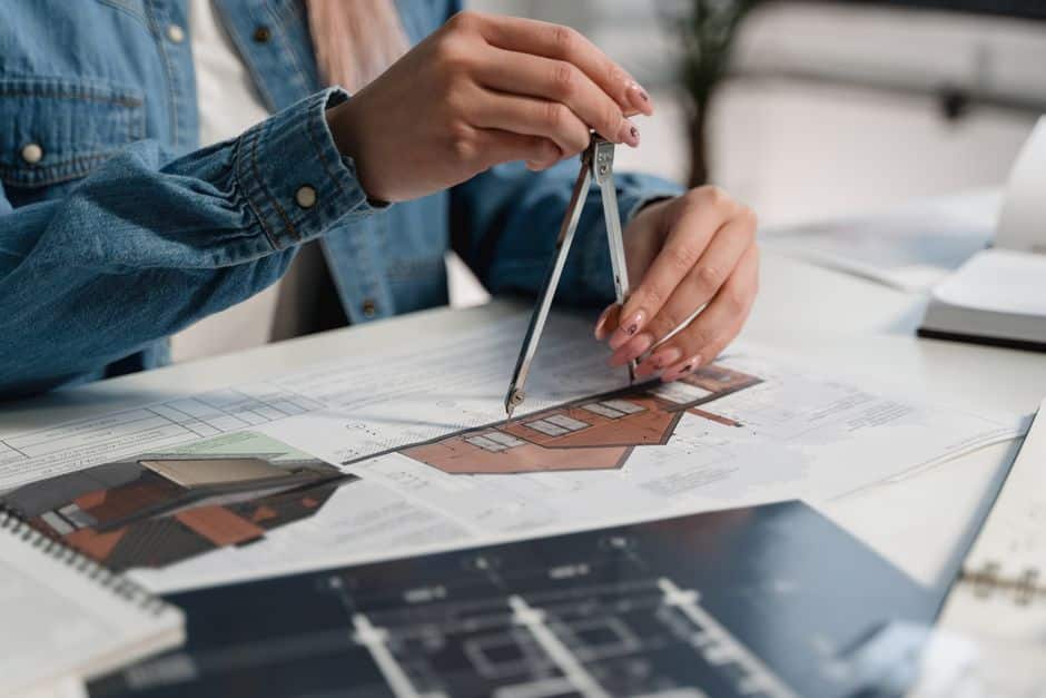 An architect carefully works on a detailed blueprint at a well-lit desk, representing the strategic framework and structured plan needed to defend a brand's SEO in AI search.
