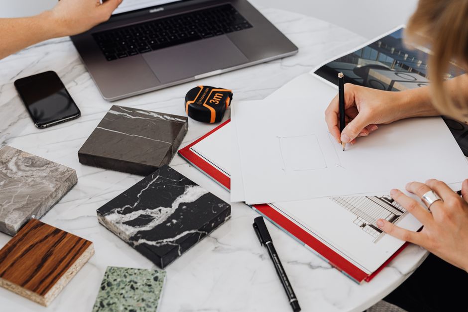 Architectural blueprints for a building laid out on a modern desk next to a laptop, symbolizing the strategic construction of a digital real estate asset.